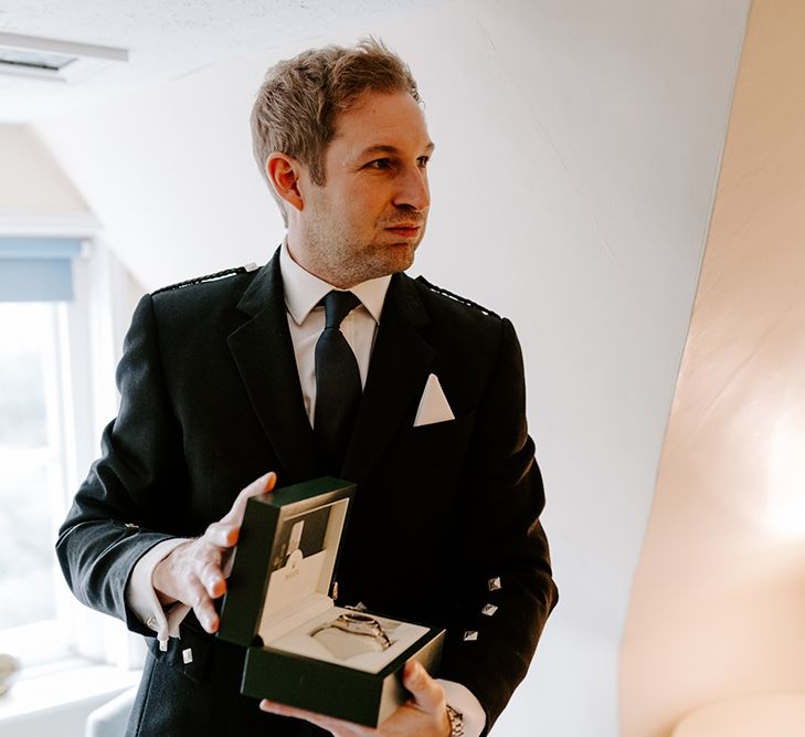 A groom opens the gift of a Rolex watch on his wedding morning