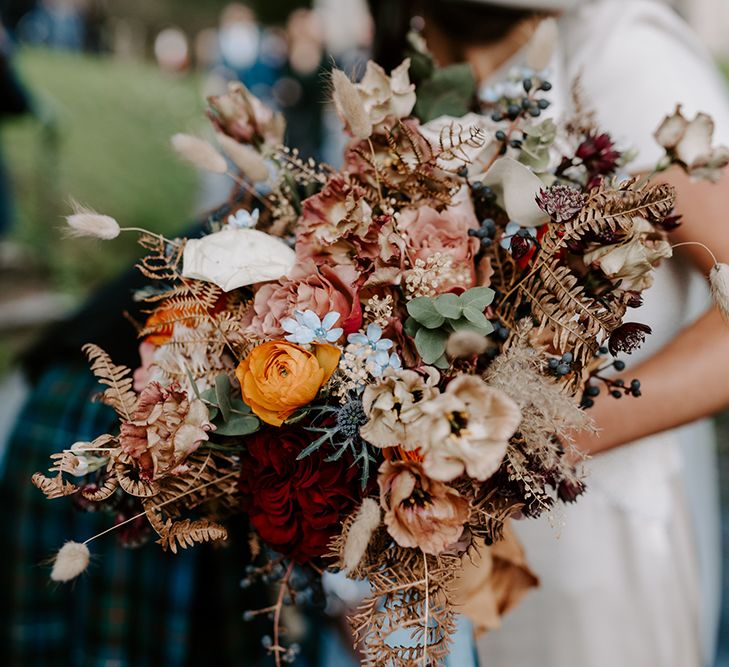 Close up of winter wedding bouquet with roses and small blue flowers. 