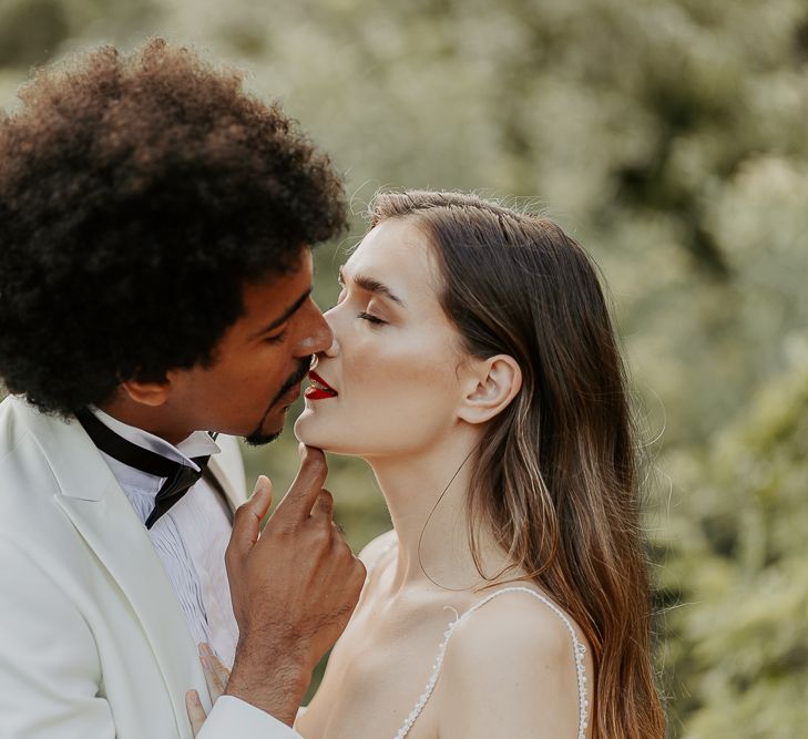 Black groom with afro hair kissing his bride with red lipstick 