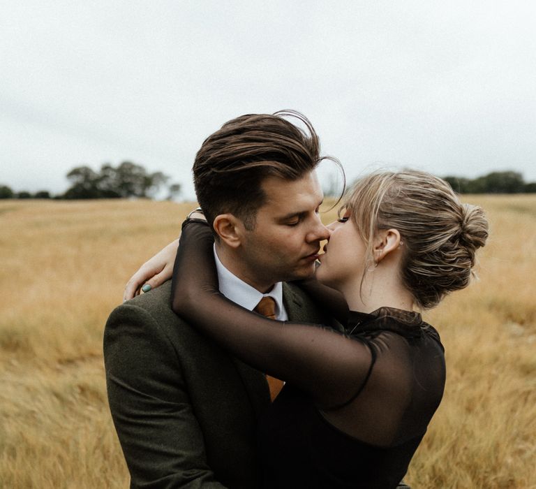 Bride & groom kiss in golden fields on wedding day