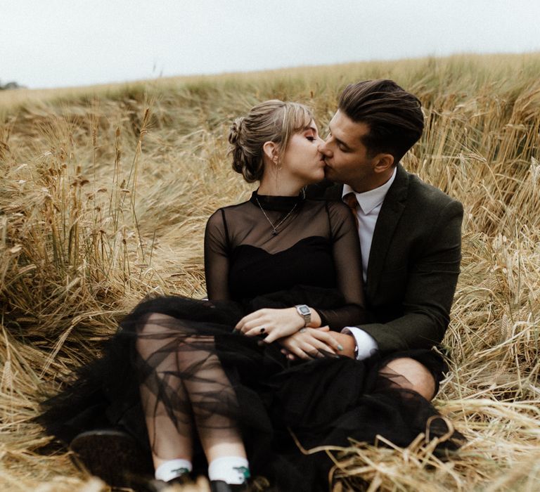 Bride & groom sit together in golden fields