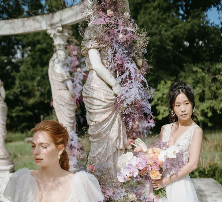 Brides stand together wearing ethereal dresses and with natural hairstyling