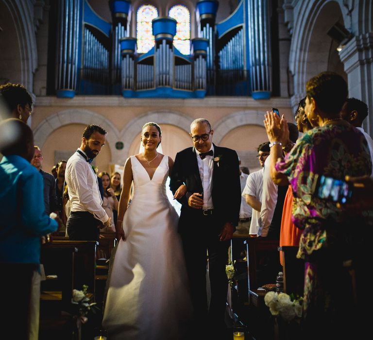 The bride walking down the aisle and smiling walking arm in arm with her father