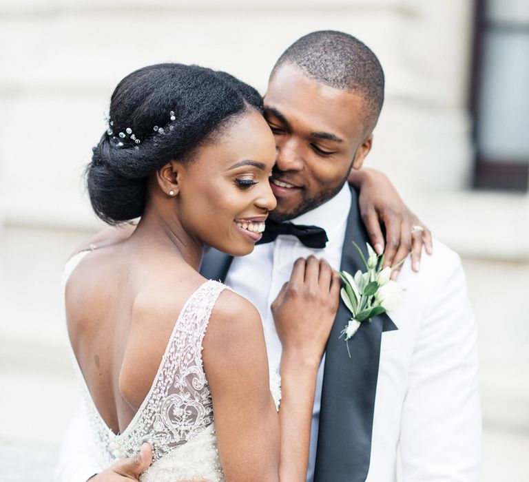 Bride & groom embrace outdoors whilst bride wears her hair in low up-do