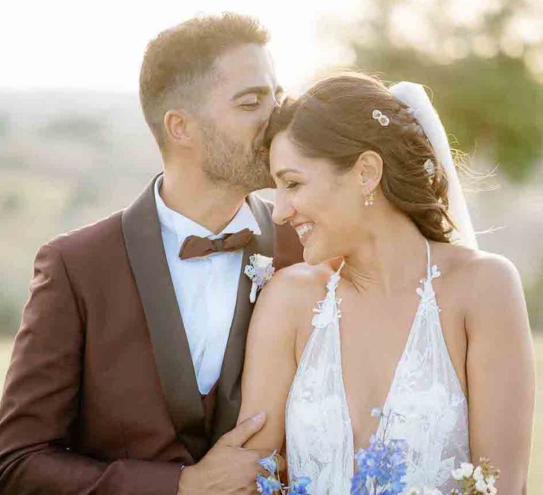 Groom in maroon wedding suit with bride in halter neck wedding dress