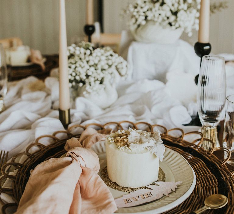 Bohemian wedding table decor with natural linens, taper candles, dried flowers and leaf design name place card and cake 