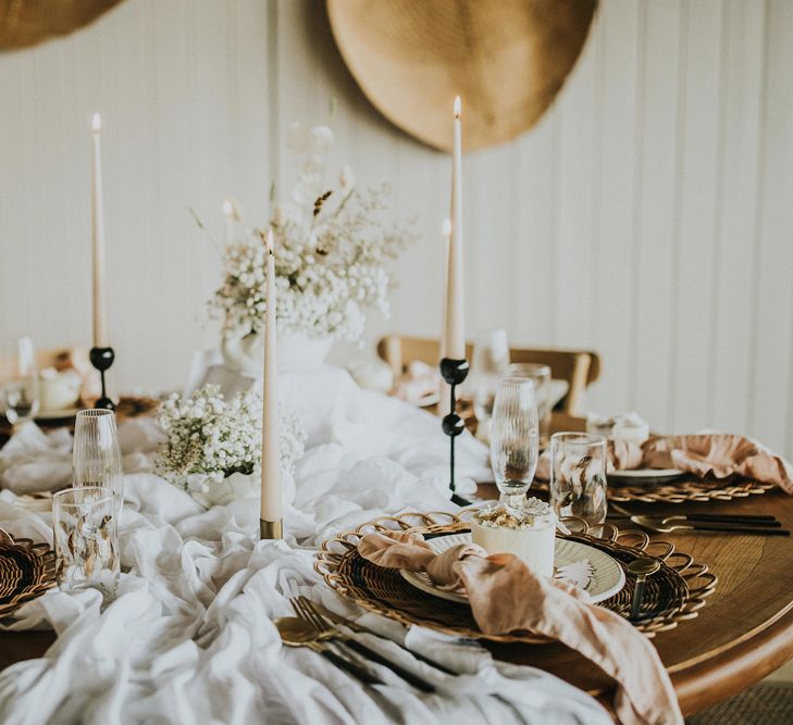 Bohemian table decor with wicker charger plates, taper candles, natural linens and individual cakes 