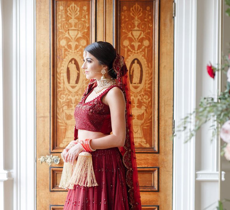 Bride stands in front of wooden doorway on wedding day