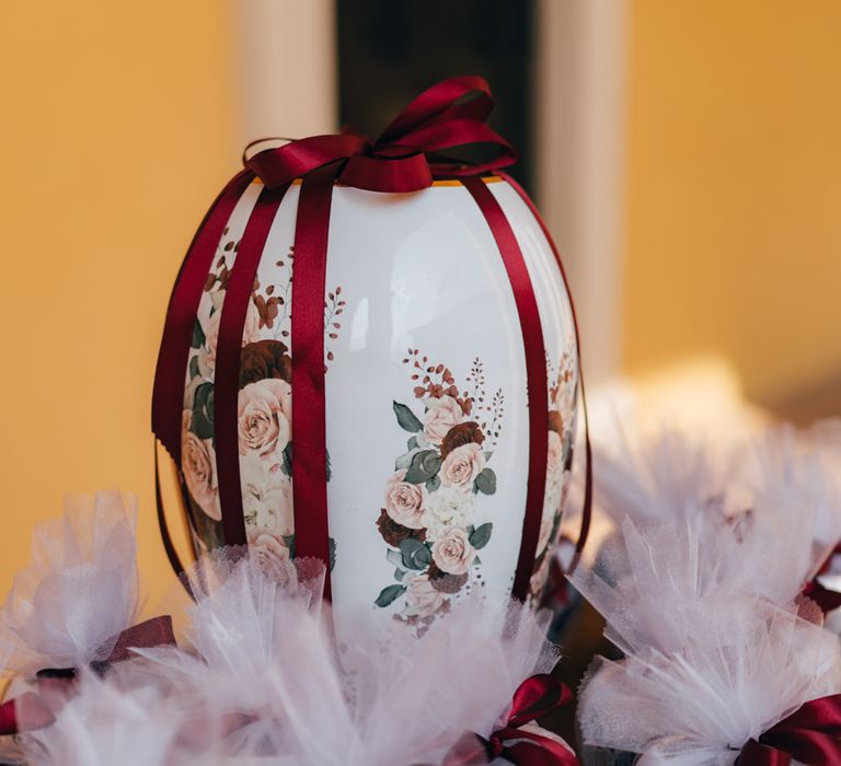 Miniature terracotta pots with floral design and burgundy ribbon made by the Groom's cousins as wedding favours