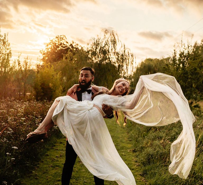 Groom tips back bride as her veil blows in the wind