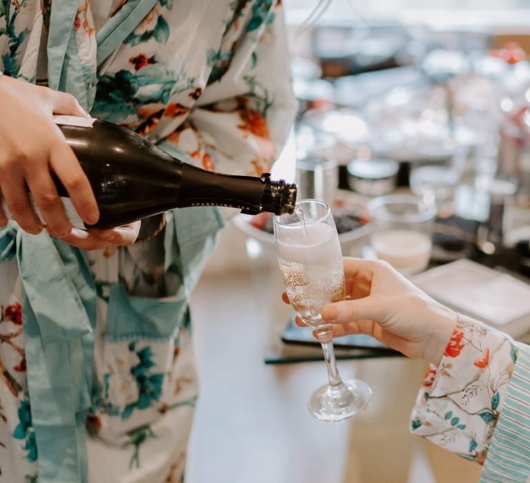 Bridesmaids pouring champagne wearing matching floral robes