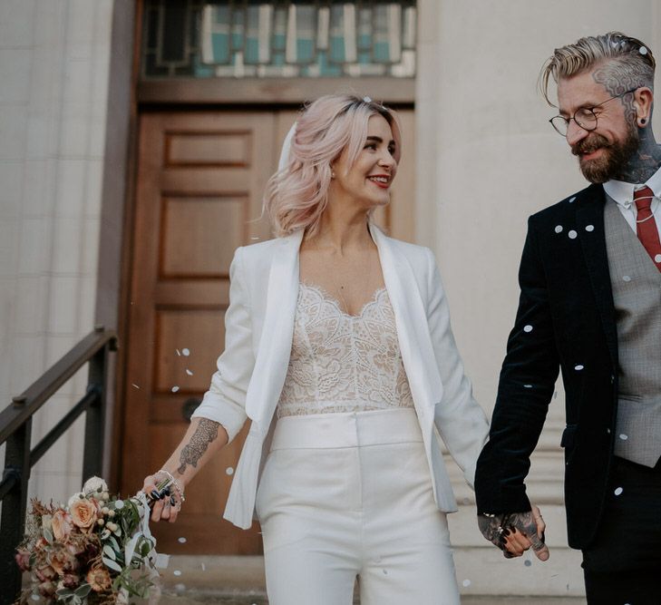 Bride and groom walk down steps as confetti is thrown