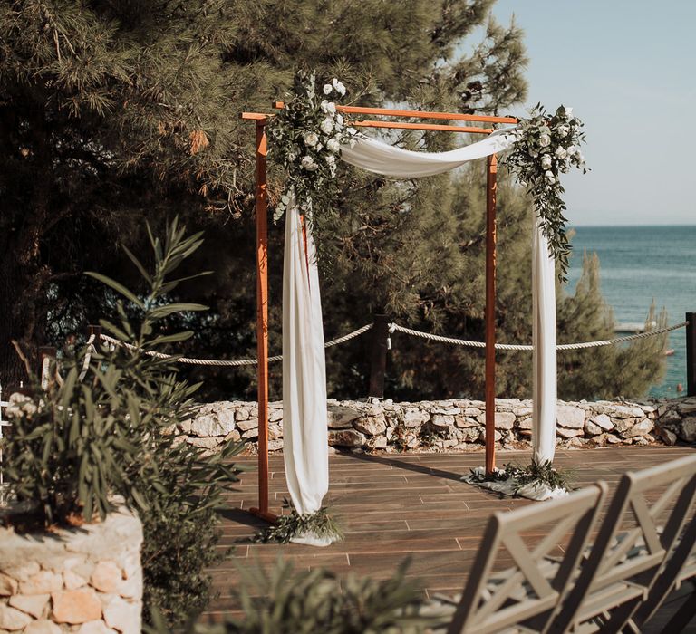 Wooden arch with white drapes and flower decor