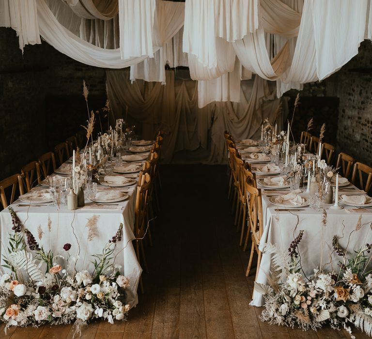 Intimate wedding reception at Pentney Abbey with draped ceiling, dried and fresh flower arrangements and taper candles 