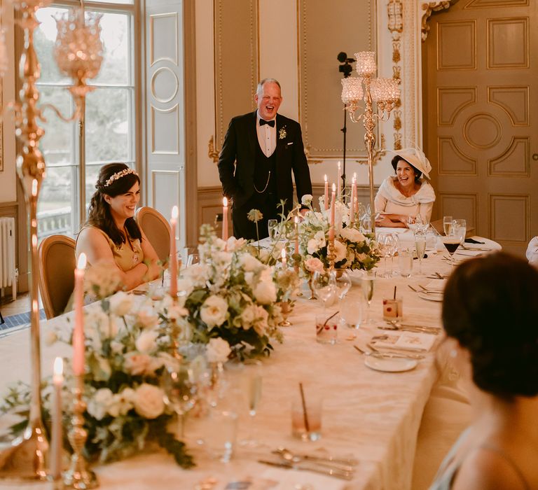 Bride & groom sit with wedding guests for wedding reception at the Markree Castle surrounded by floral bouquets 