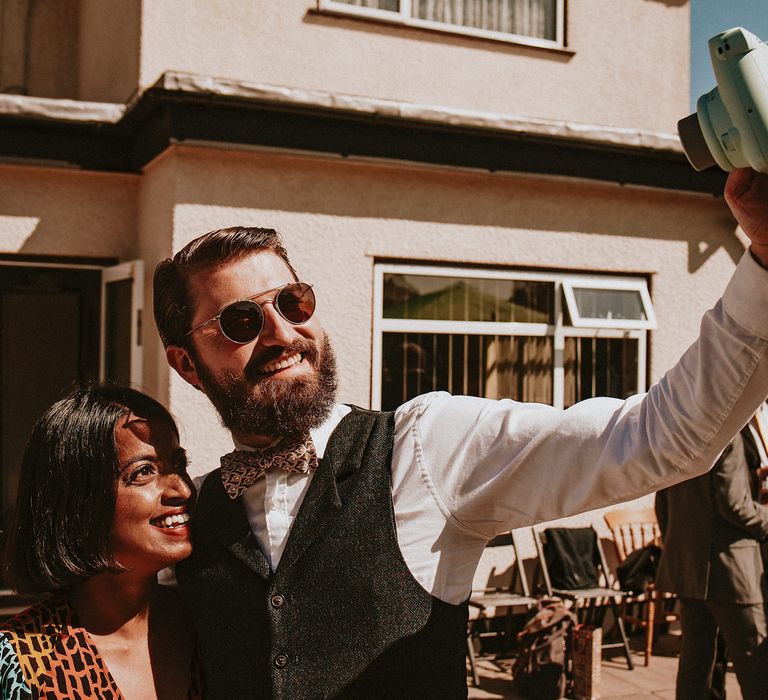 Wedding guests talking a polaroid selfie at a garden party wedding reception