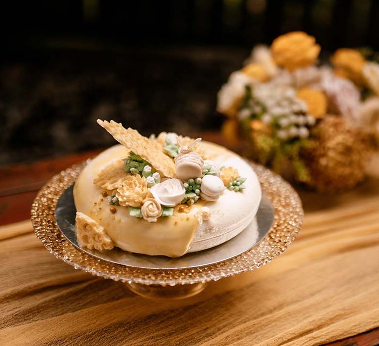 Wedding cake on a gold cake stand with with honeycomb and macaroon decor 