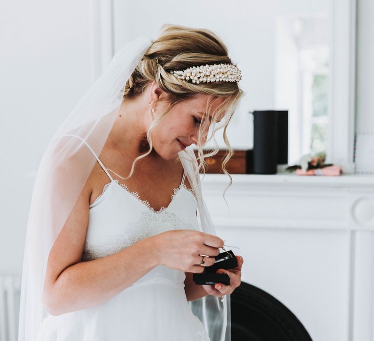 Bride looks at wedding gift on her wedding day as she smiles 