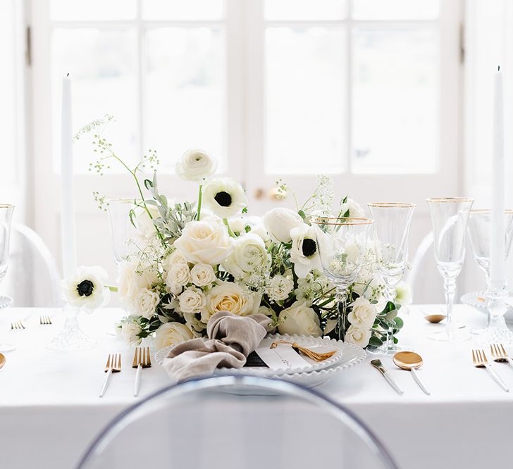 A black and white wedding bouquet rests on a table including ranunculus, roses and anemones.