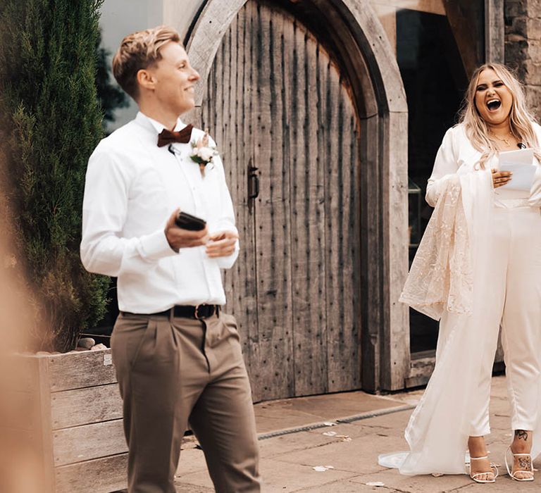 Brides laugh during speeches outdoors on their wedding day