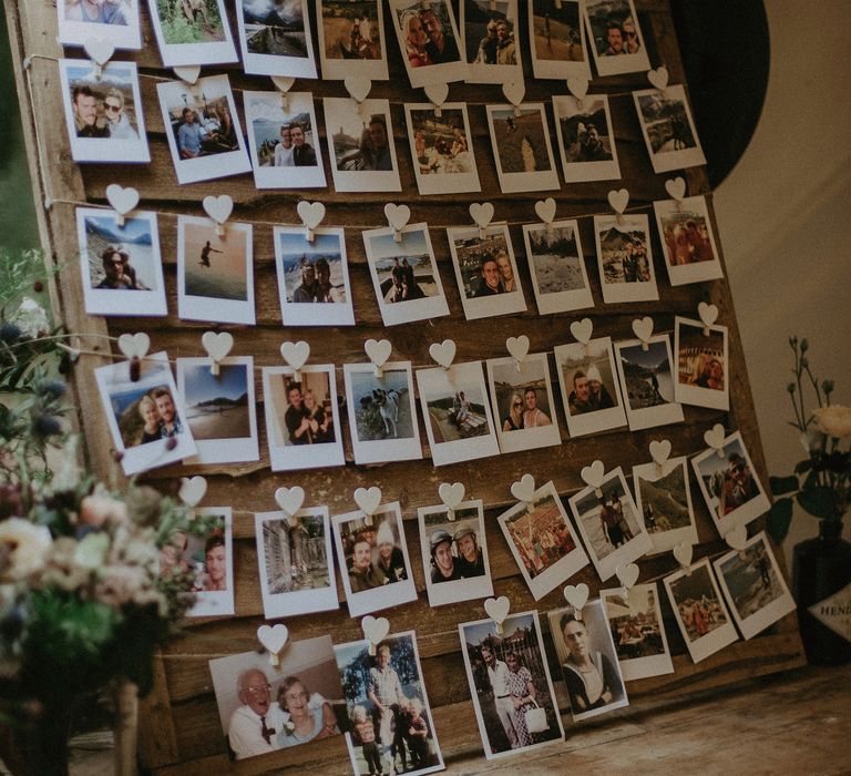 Polaroid pictures of couple stuck up with little white hearts on wooden board