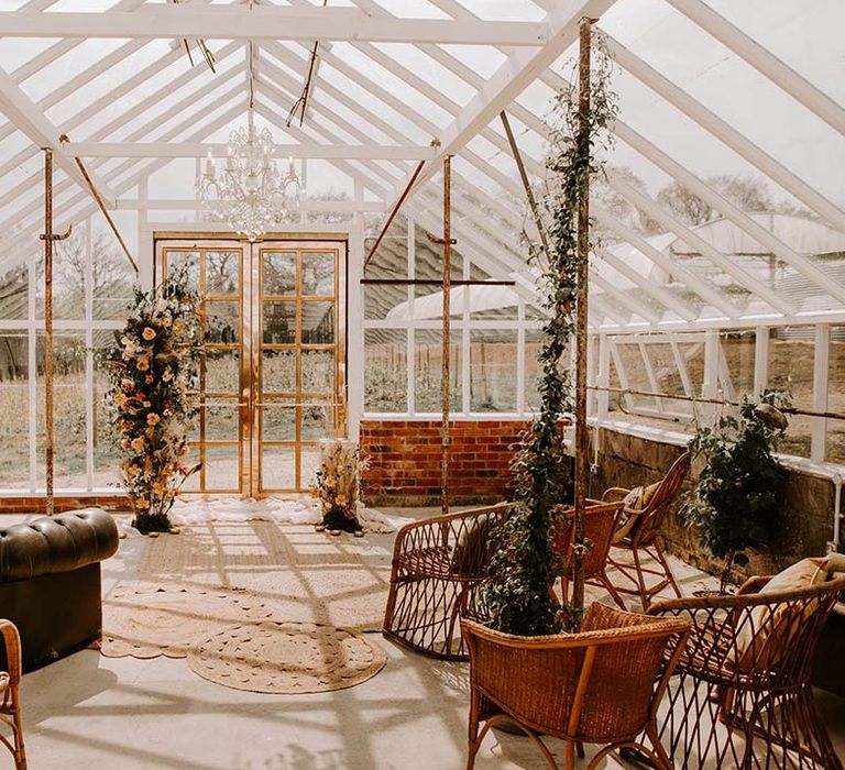 The conservatory at Gooseberry House with vertical floral arrangements, wicker and vintage chairs 