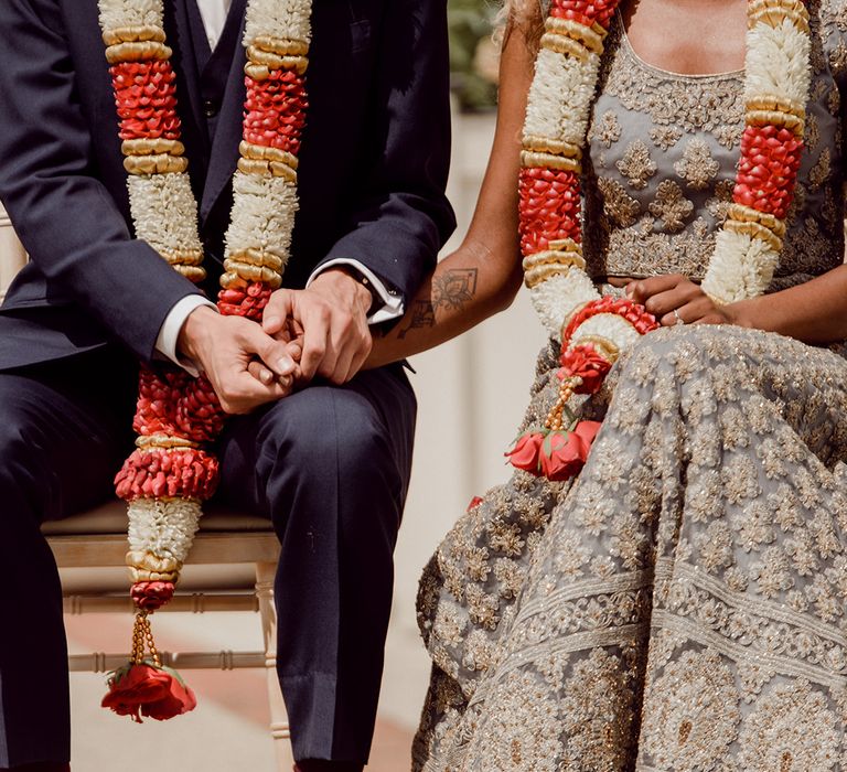 Bride & groom wear colourful garlands around their neck on wedding day during ceremony | Joshua Gooding Photography