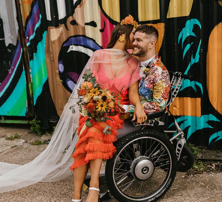 Colourful Shoreditch elopement with interabled couple, The Wheel Life kissing in front of the street art 