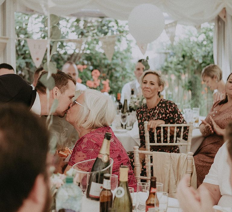 Groom kissing his mum during the at home marquee wedding reception 