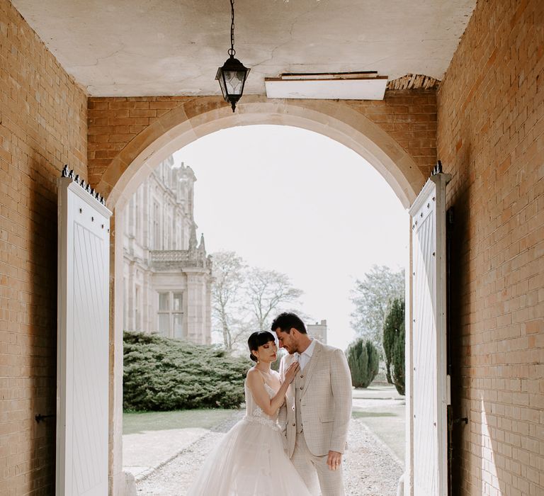 Bride and groom portraits at Bylaugh Hall with South Asian bride in a princess wedding dress and groom in a beige check suit