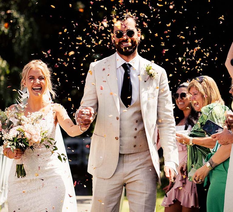 Bride and groom confetti moment at outdoor wedding