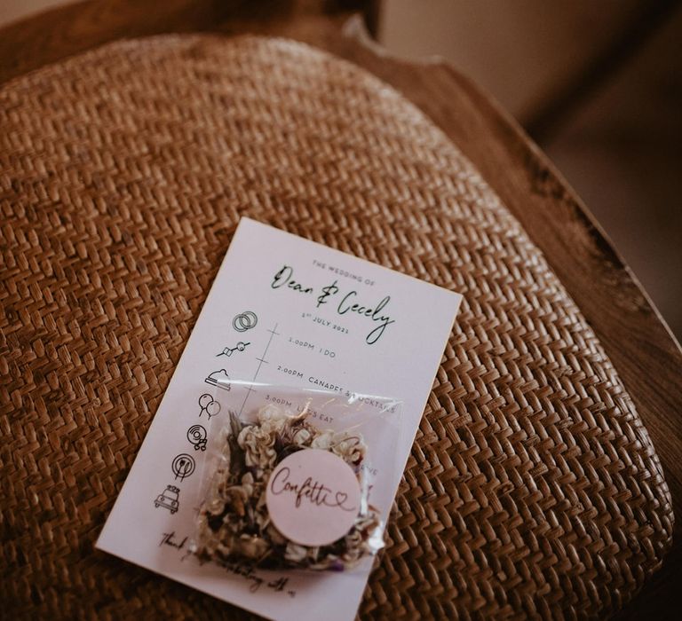 Wedding stationery sits on wicker chair complete with dried confetti