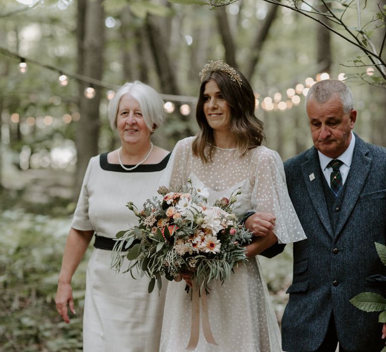 Bride walks down the aisle with her parents on wedding day