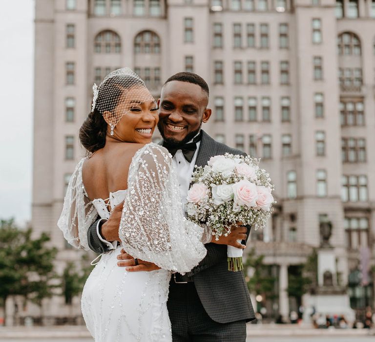 Bride & groom hug on their wedding day whilst smiling 