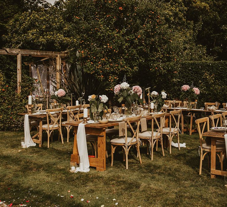 Garden reception setting complete with wooden tables for intimate reception