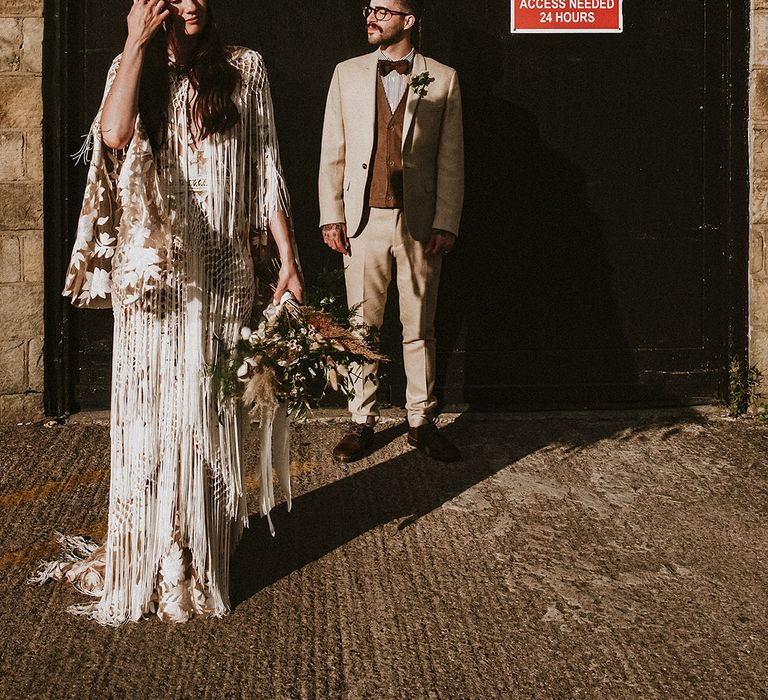 Bride & groom stand together outdoors in the sunshine