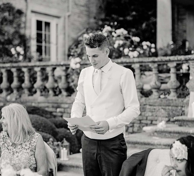 Groom gives speech during wedding reception outdoors 