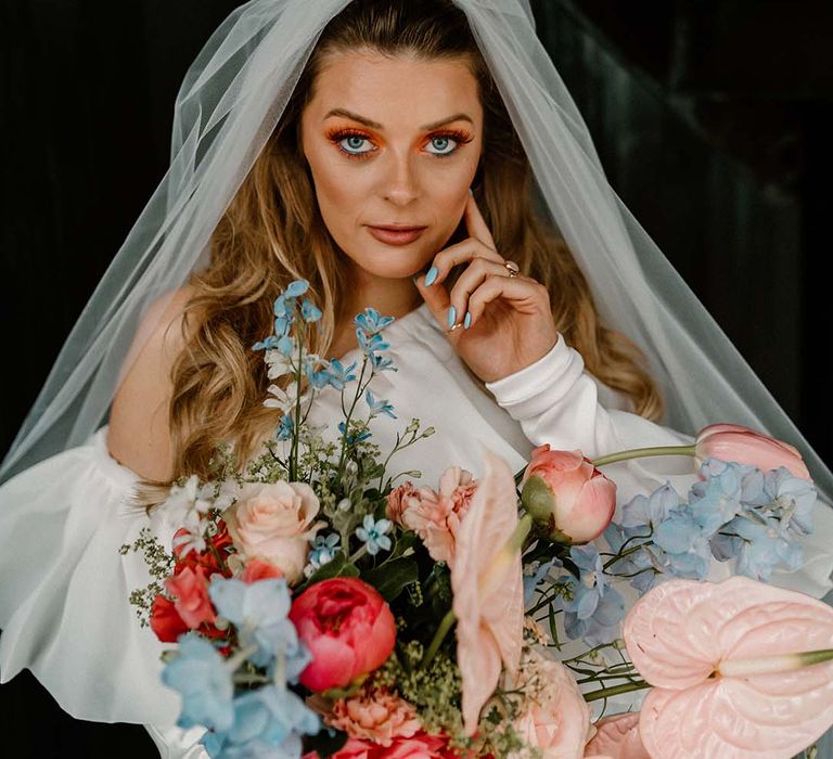 Bride with coral eyeshadow wedding makeup and blue nails to match the vibrant wedding bouquet 