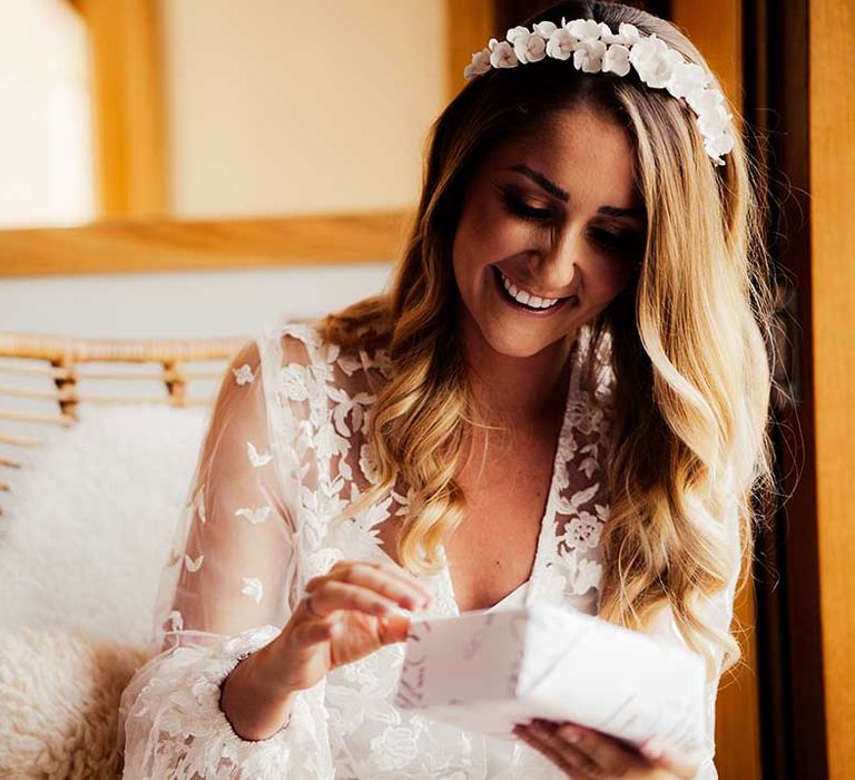 Bride in white flower headband and white lace wedding dress opening present on the morning of her wedding 