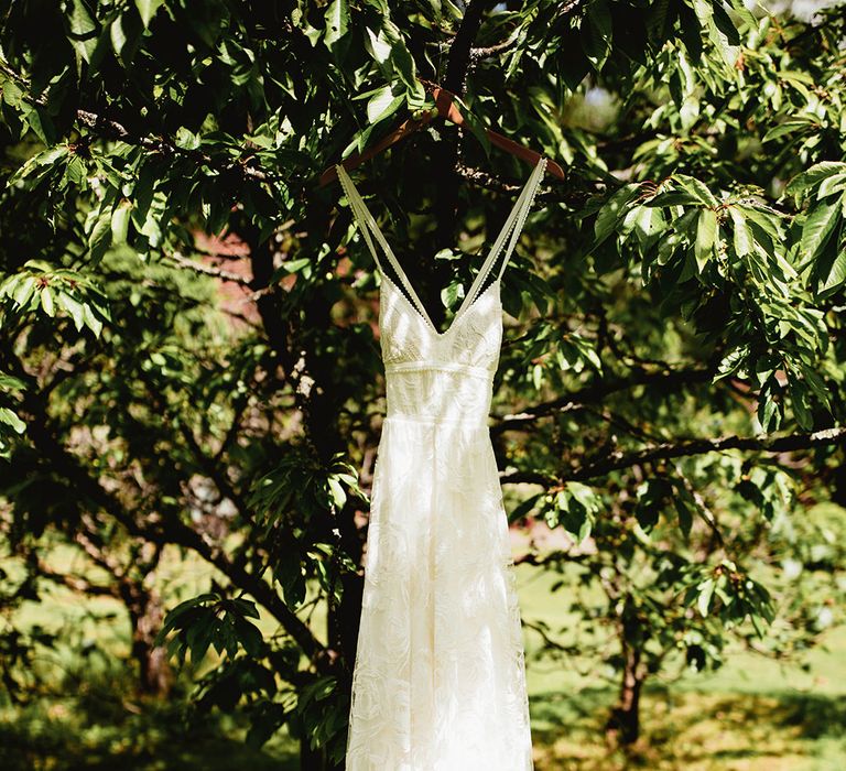 Bride's lace boho wedding dress hanging from tree