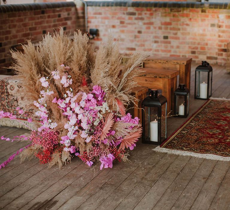 Prestwold Hal Barn wedding venue with wool rug, benches and pink cherry blossom and pampas grass floral arrangements 