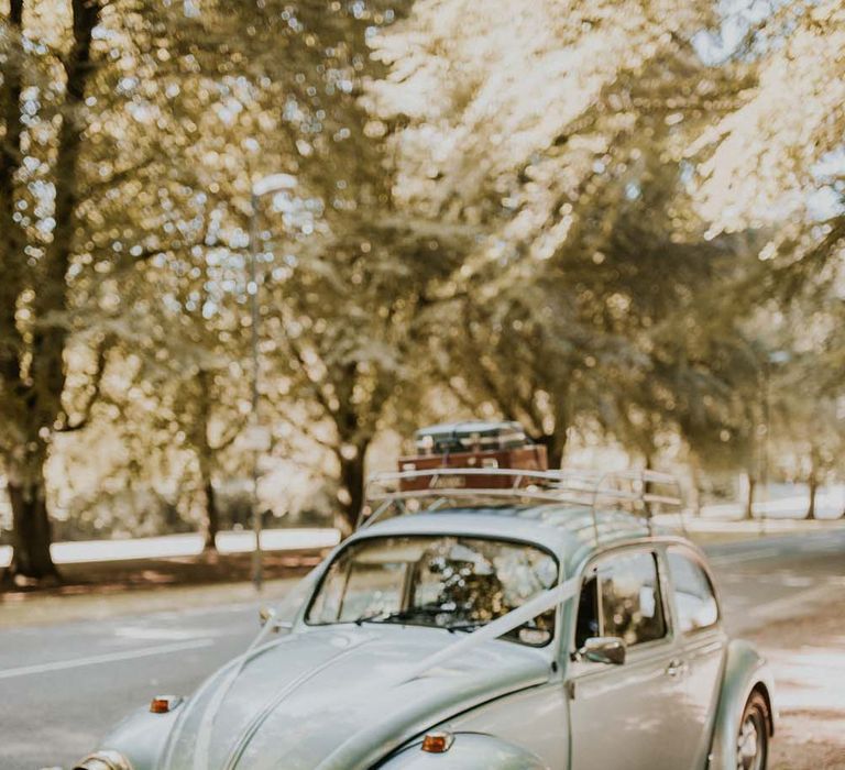 Baby blue beetle wedding car with vintage suitcases on top and floral front