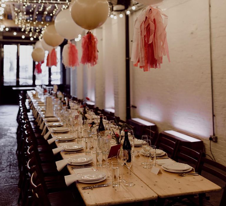 100 Barrington wedding venue decorated with white balloons and pink tissue paper tassels, fairy lights and long banquet tables with simple table settings