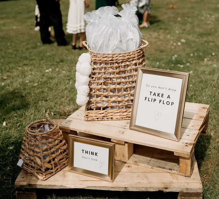 Wicker basket with sheer white bags of white flip flops for the outdoor wedding celebrations