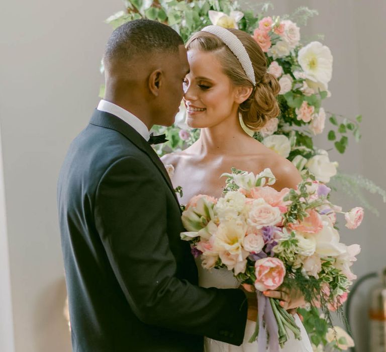 Groom in black tie for Manor House wedding with bride smiling at him in a strapless wedding dress 