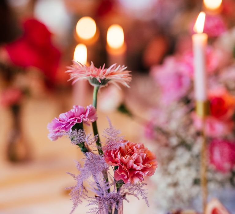 Small brightly coloured floral arrangement in purple vase