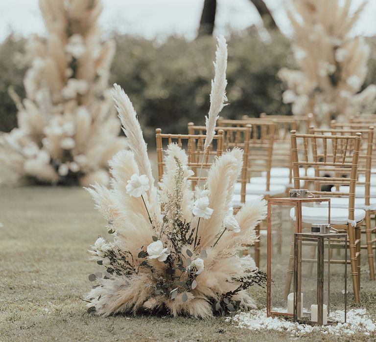 Pampas grass wedding flowers line the aisle of outdoor wedding in Phuket 