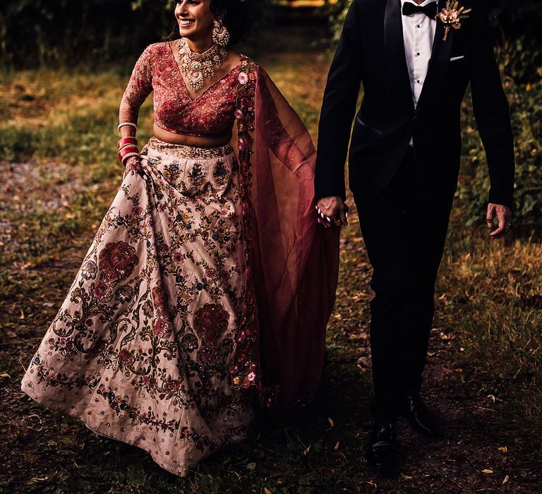 Bride walks with her groom who wears black tie and pampas grass buttonhole 