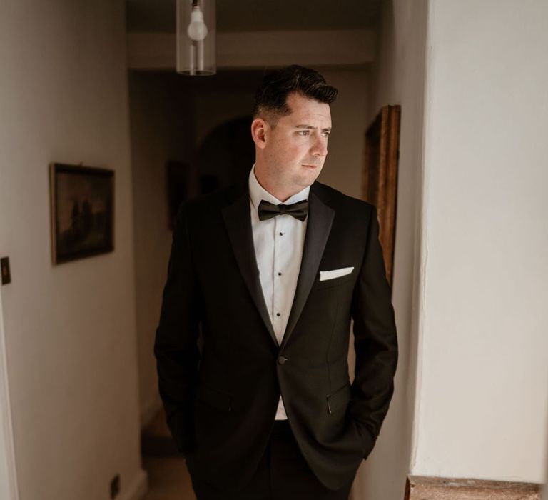 Groom in black tie stands for his classic country house wedding 