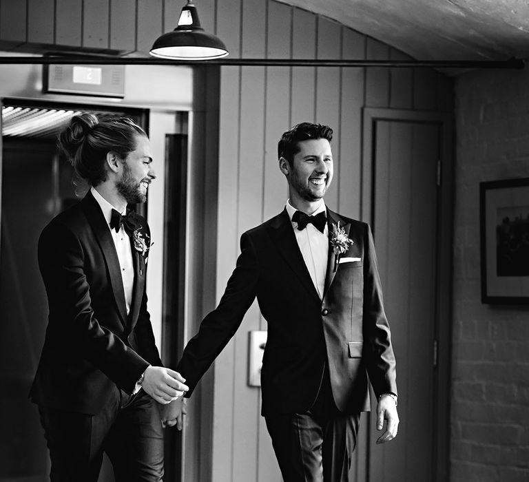 Grooms hold hands as they walk together on their wedding day